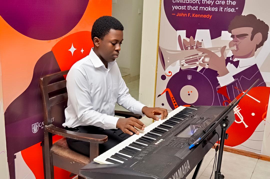 Student playing keyboard beside jazz mural